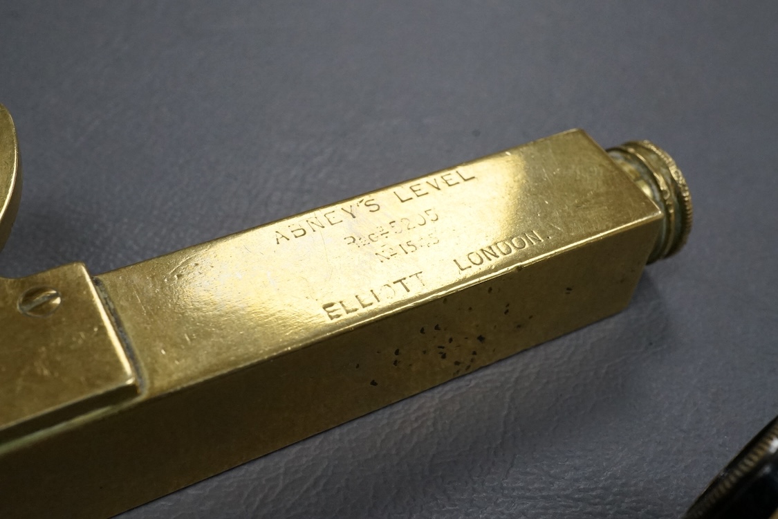 A brass Abney’s level by Elliott, London, 12cm long, together with a pair of folding brass miniature binoculars, 10cm wide.